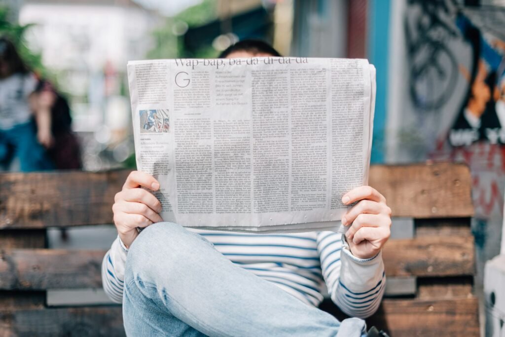 Cómo aparecer en Google Discover: guía para medios 3 Persona leyendo un periódico en un banco
