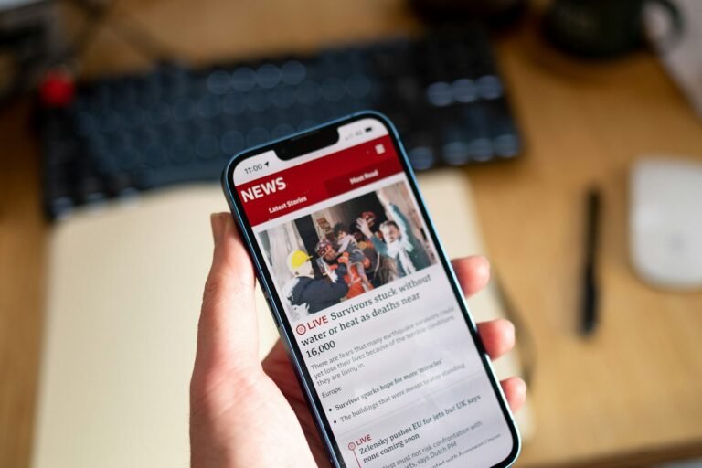 Mano sosteniendo un móvil con una web de noticias abierta