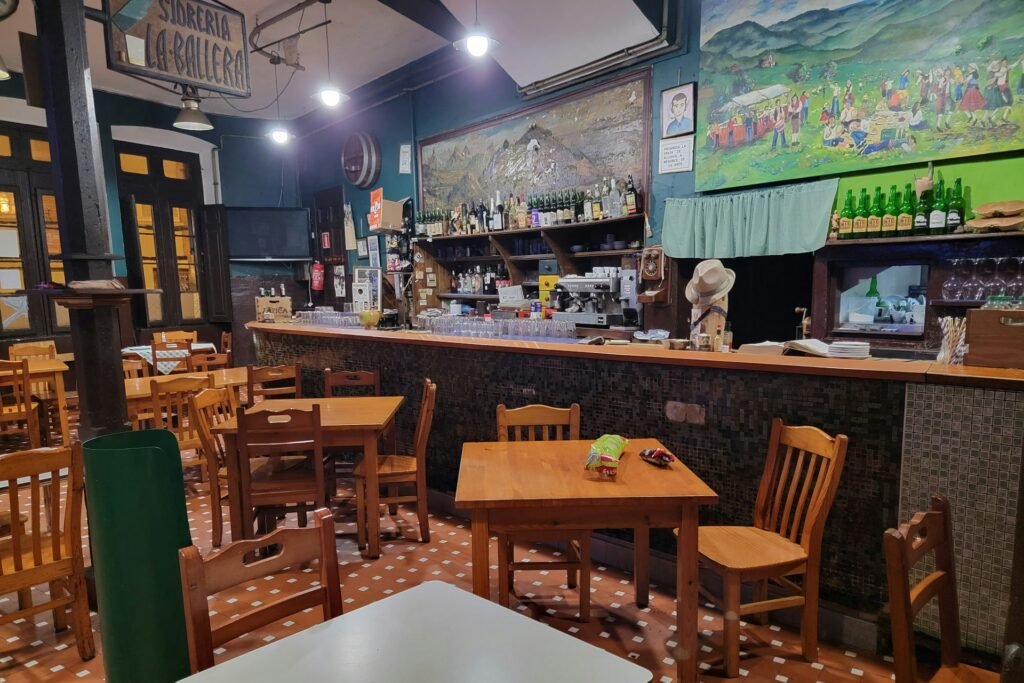 Interior de un bar restaurante con barra y mesas de madera